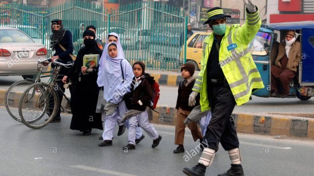 schoolchildren-walk-past-a-traffic-policeman-as-they-cross-the-road-h5ey7k