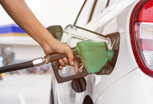 Hand holding fuel nozzle to refuel gasoline for car at petrol fi
